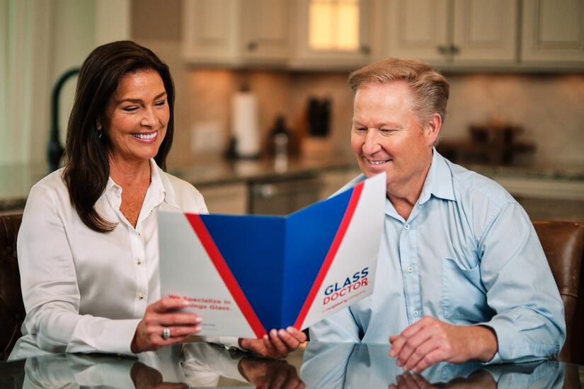 Woman and man looking at Glass Doctor folder with options for custom glass mirrors